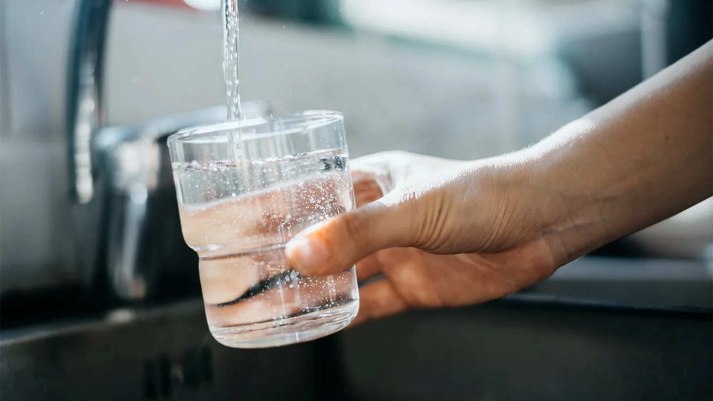 A glass of water being filled at a kitchen tap